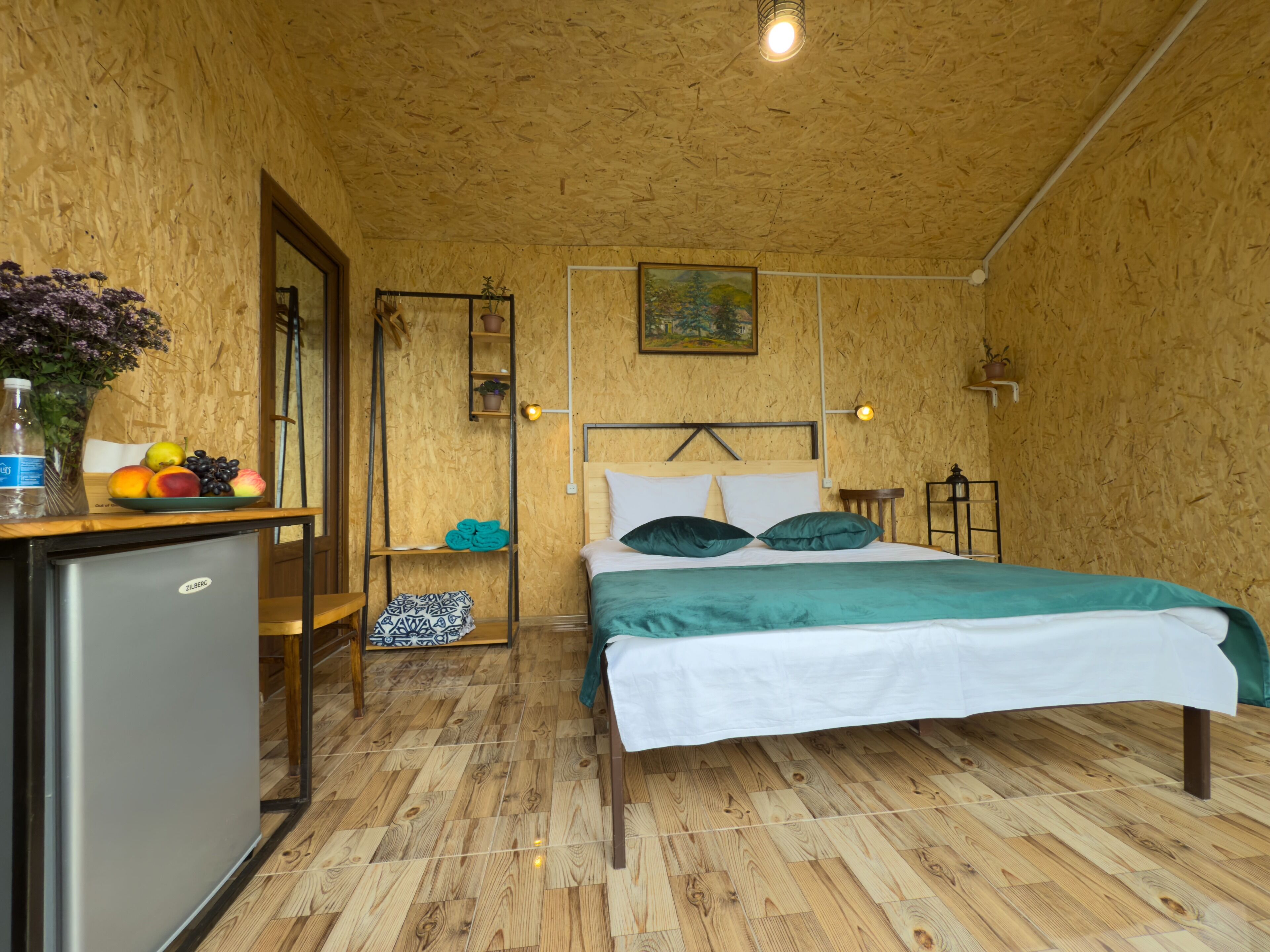 A compact room with a bed, a small desk, and a refrigerator.