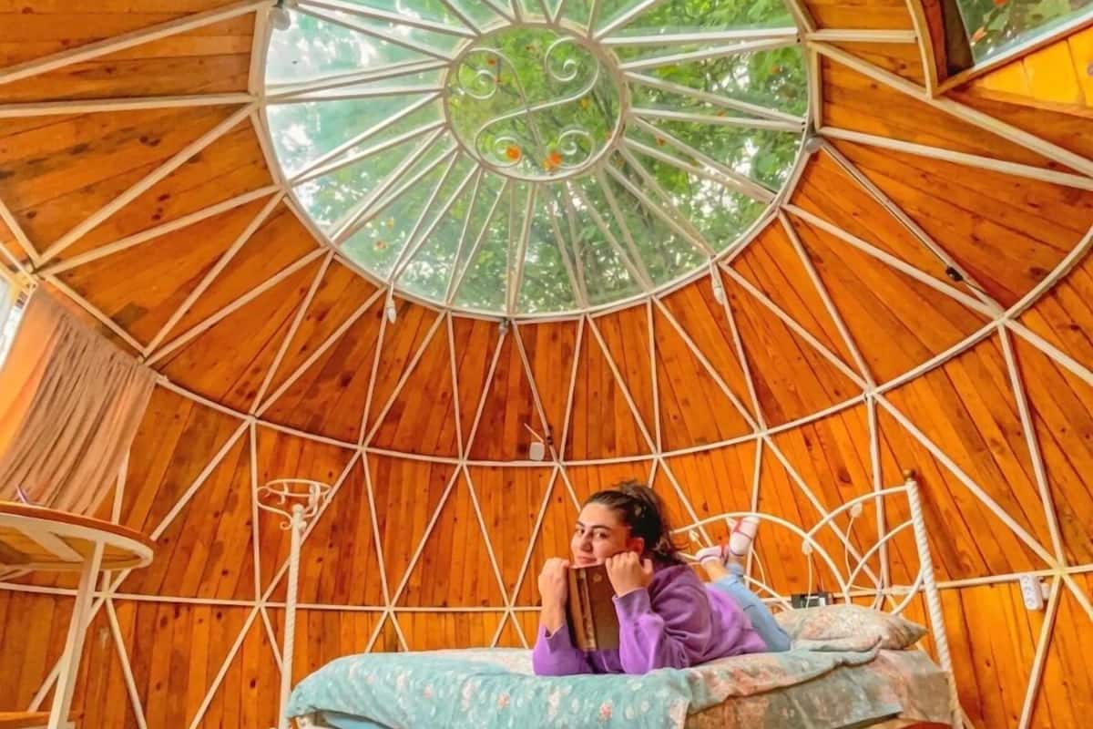 A circular wooden room with a bed and a window.