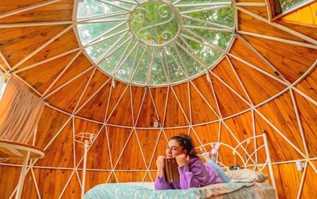 A circular wooden room with a bed and a window.