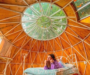 Une pièce circulaire en bois, avec un lit et une fenêtre.