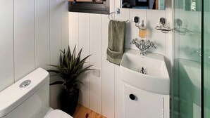 Un baño pequeño con inodoro, lavamanos y una planta en maceta.