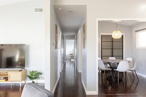 Una sala de estar moderna con una televisión de pantalla plana, un sofá y un comedor con mesa y sillas.