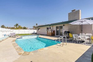 A swimming pool with a patio area, including a barbecue grill and outdoor seating.