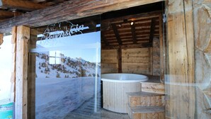 Eine Holzhütte mit Glastür, Whirlpool und Holztreppe.