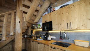 Eine Holzhüttenküche mit integriertem Mikrowellenherd, Holzschränken und einer Holz Arbeitsplatte.