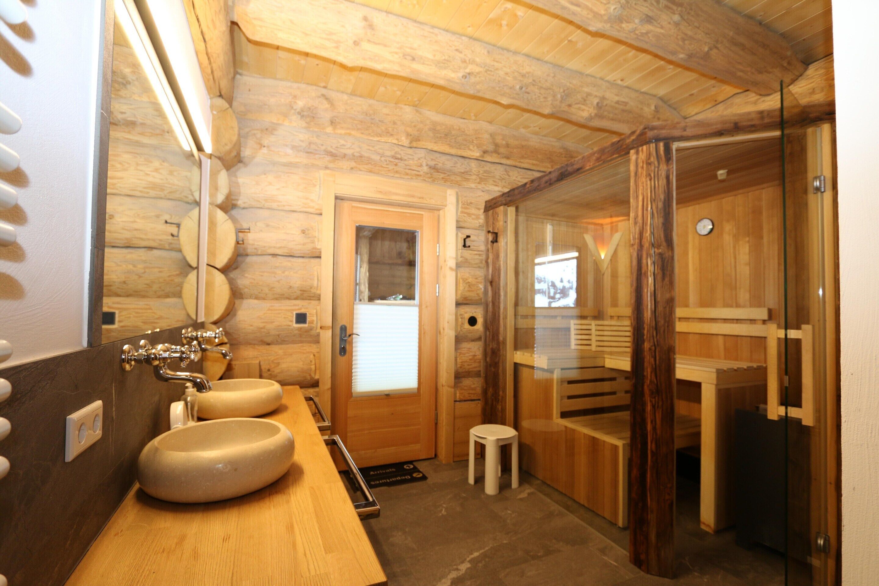 Un baño estilo cabaña de madera con un banco de madera, un lavabo y un box de ducha de vidrio.