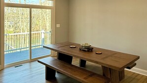 A dining area with a wooden table and benches, a sliding glass door leading to a balcony, and a light switch on the wall.