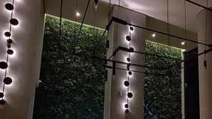 A modern reception area with a wooden floor, a reception desk, and a green wall with vertical gardens.