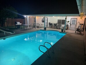 A swimming pool with a slide, surrounded by outdoor seating and a covered patio area. - Level up lounge home. Great family retreat! (McAllen)