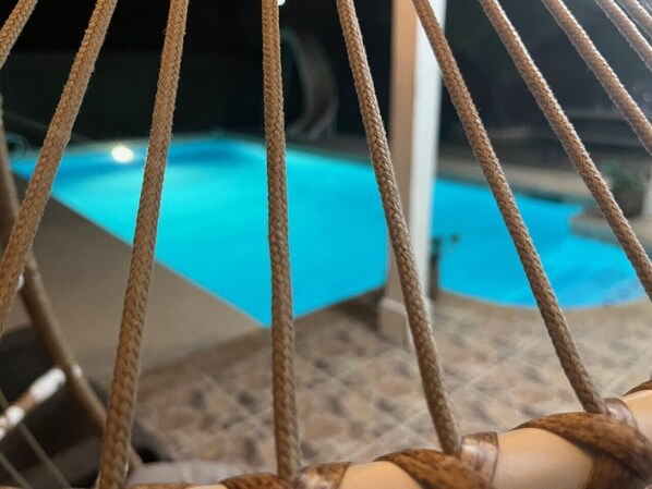 A rope chair with a view of a swimming pool. - Level up lounge home. Great family retreat! (McAllen)