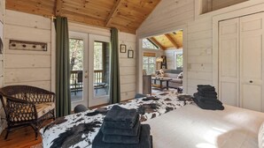 Una habitación acogedora con una cama, un sillón de mimbre y vistas a la terraza exterior.