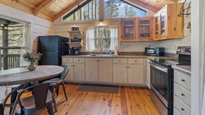 Una cocina con armarios de madera, un refrigerador negro, un microondas y una estufa.