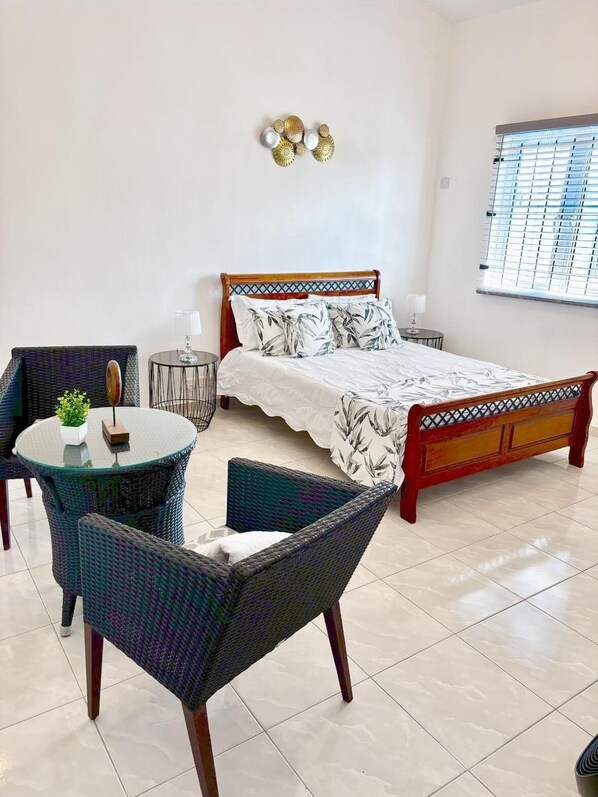 Relax in this inviting space with a single bed, round table, and wicker chairs.