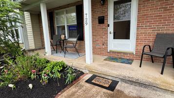 A two-story house with a brick facade, a front porch with a bench, and a mailbox.