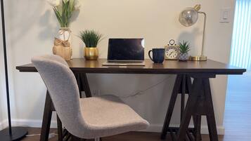 A modern workspace with a laptop, a clock, a coffee mug, and decorative plants on a wooden desk.