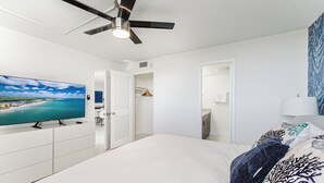 Une chambre à coucher comprenant un lit, un téléviseur, un ventilateur de plafond et une armoire.