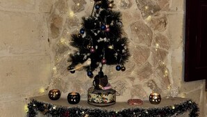 Une cheminée avec un sapin de Noël, entourée d’objets décoratifs et d’un mur en pierre.