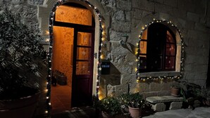 Un bâtiment en pierre doté de deux fenêtres en arc de cercle et d’une porte, le tout décoré de guirlandes lumineuses.