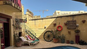 Un espace piscine aménagé avec des chaises longues, un fauteuil roulant et des plantes en pot.