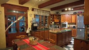 Une cuisine avec des meubles de rangement en bois, un îlot central et une table à manger avec des chaises.