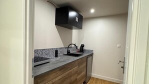 Une cuisine de taille réduite, dotée d’un plan de travail foncé, d’un meuble noir et d’un pare-feu en carreaux.