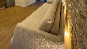 Un salon moderne avec un canapé, un mur décoratif en pierre et une vue sur un paysage enneigé, visible à travers une grande fenêtre.