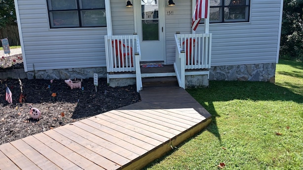 Une petite maison avec un porche, une boîte aux lettres et un drapeau américain.