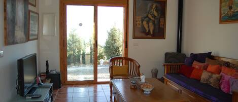 A living room with a wooden table, a sofa, a television, and a large window.