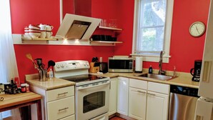 Une cuisine de taille réduite, dotée de meubles blancs, d’un lave-vaisselle en acier inoxydable, d’un four à micro-ondes et d’une cuisinière.