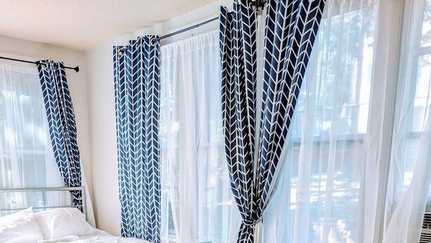 Une chambre à coucher avec un lit, une armoire en bois, une table ronde, un canapé et un tapis bleu.
