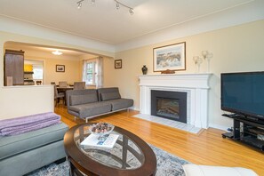A living room with a fireplace, a sofa, a coffee table, and a television. - The Forrester Vista (Oak Bay North)