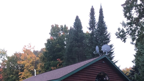 Tunnelmallinen hirsihökkelö, jossa on kivinen pohja, ulkona oleva oleskelualue ja suuri ikkuna.