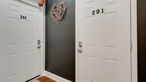 Un pasillo con dos puertas blancas, identificadas con los números 200 y 201, una pared oscura y una decoración de corazón en la pared.
