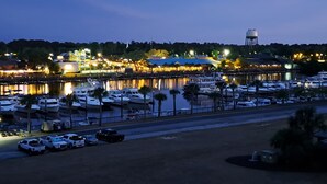 Uma marina com barcos atracados, um reservatório de água e um edifício com janelas iluminadas.
