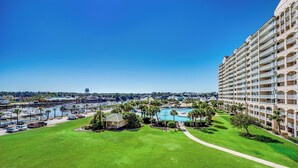 Um hotel com uma piscina grande, palmeiras e vista para a água.