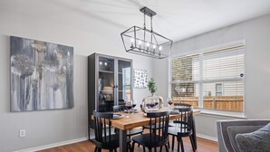 A dining area with a wooden table, black chairs, a chandelier, and a large abstract painting on the wall. - Spacious 5BR / Perfect for Families & Groups (Universal City)