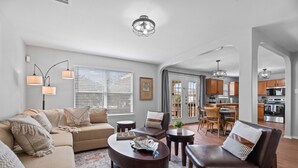 A modern living room with a sofa, coffee table, and dining area. - Spacious 5BR / Perfect for Families & Groups (Universal City)