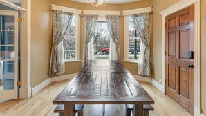 A dining room with a wooden table, floral curtains, and a view of the outside. - Spacious main level 2 bdrm off Missoula Hip Strip, across river from downtown (Missoula)