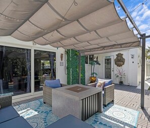 Un espace extérieur aménagé avec un patio couvert, une porte vitrée donnant sur une pièce et un mur décoratif agrémenté de plantes.