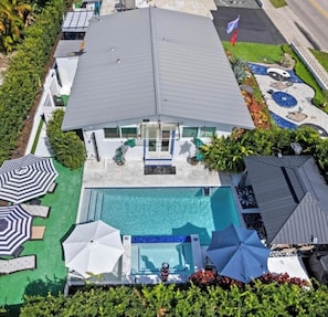 A modern house with a swimming pool, outdoor umbrellas, and a flag.