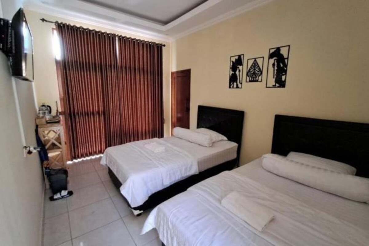 Una habitación de hotel con dos camas, un televisor y una cortina.