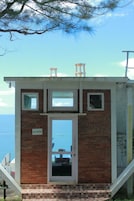 Um pequeno edifício de tijolos com uma placa indicando sala VIP, uma janela e vista para o mar.
