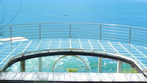 A glass-enclosed observation deck with a curved railing overlooking a body of water. - Teras Kaca (Panggang)