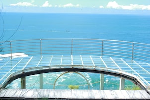 Um deque panorâmico envidraçado com guarda-corrimão curvo, com vista para um corpo de água.