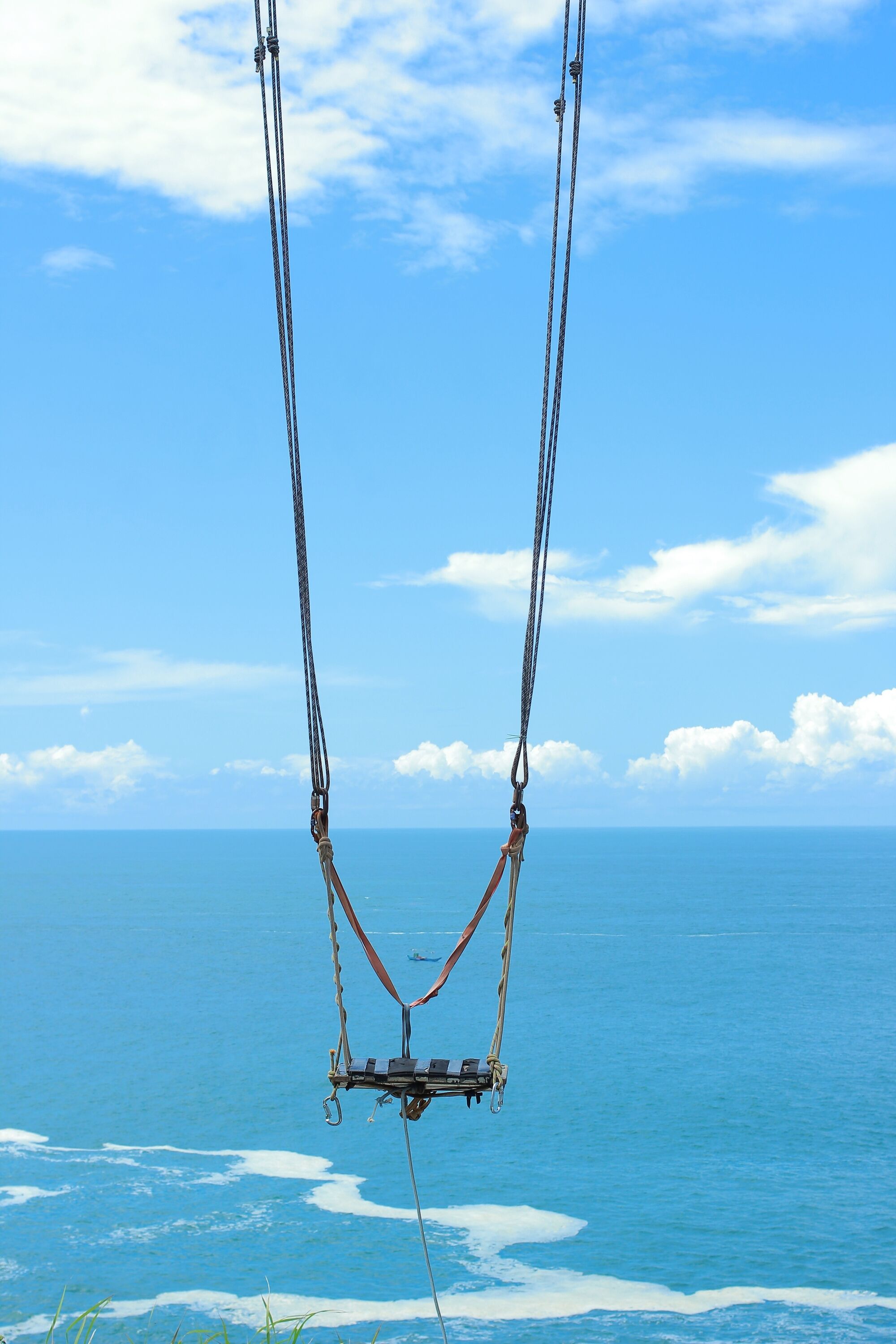 A view of the ocean with a clear sky and a rope structure in the foreground.
