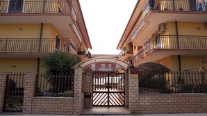 A gated entrance to a residential building with a brick wall, metal gate, and a small archway. - B&B Casa Mauro (Linguaglossa)