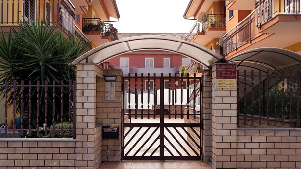 A gated entrance to a building with a brick facade, a metal gate, and a sign indicating a medical clinic. - B&B Casa Mauro (Linguaglossa)