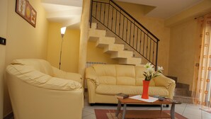 A living room with two yellow sofas, a coffee table, and a staircase. - B&B Casa Mauro (Linguaglossa)