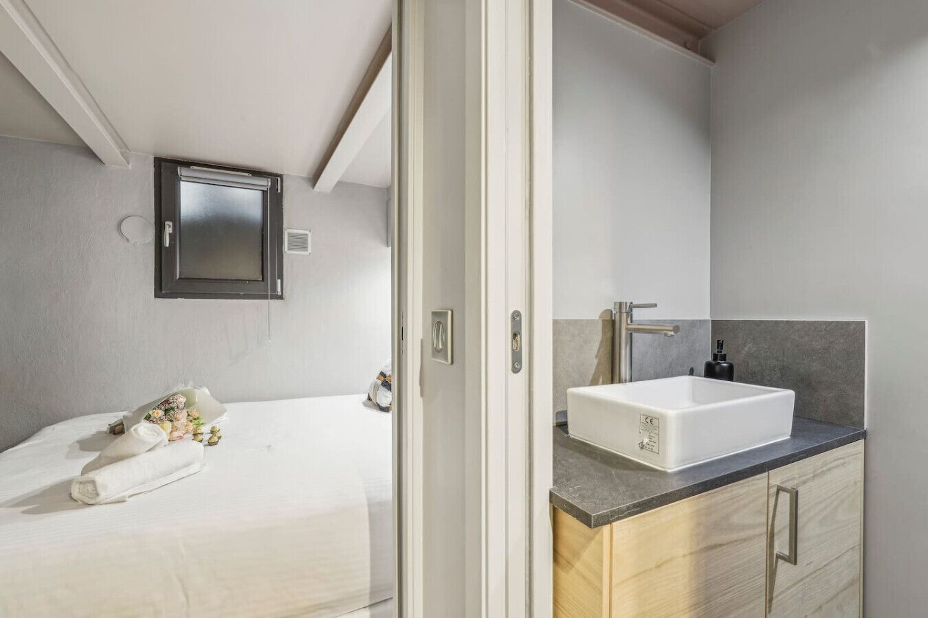 A modern bedroom with a large bed, a bedside table with a lamp, and a wall-mounted TV.