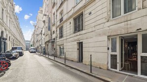 A street with buildings on both sides, parked cars, and a visible restaurant entrance.